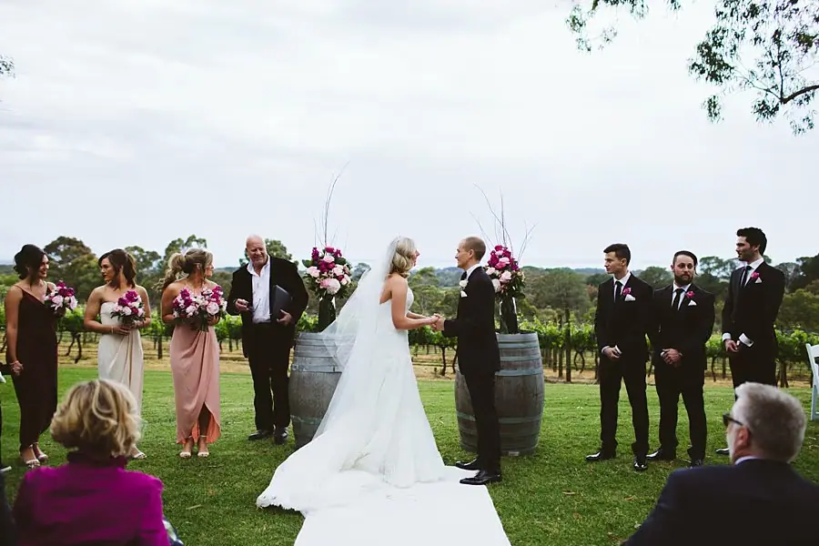 Wide view of the bride and groom meeting at the outdoor ceremony with their wedding party beside them.