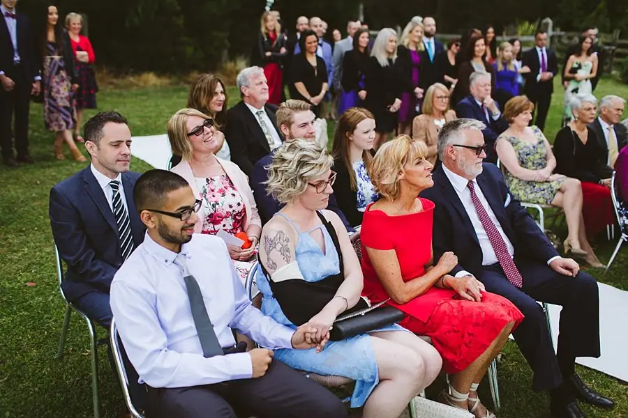 Wedding guests seated together and watching the outdoor ceremony.