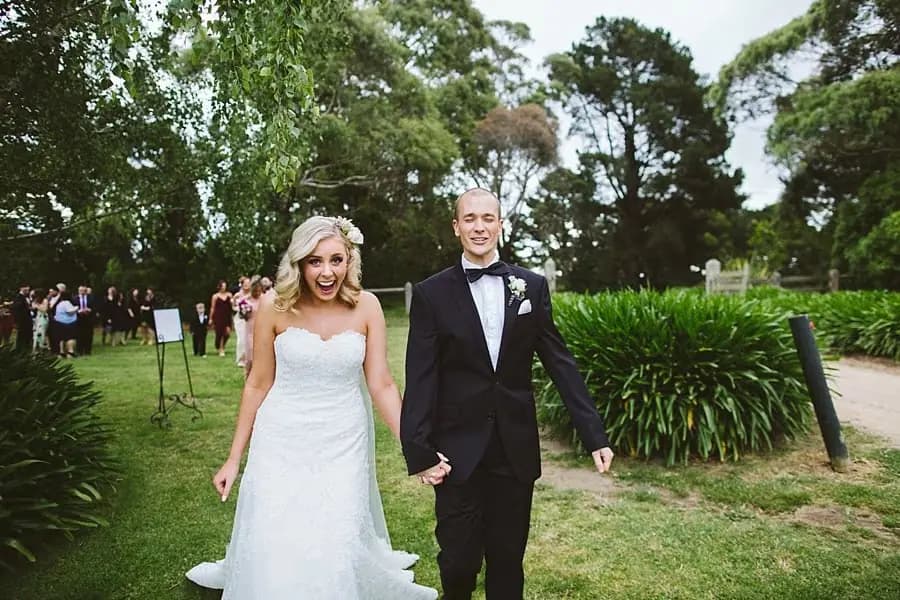 Bride and groom walking hand in hand across the lawn after their ceremony.