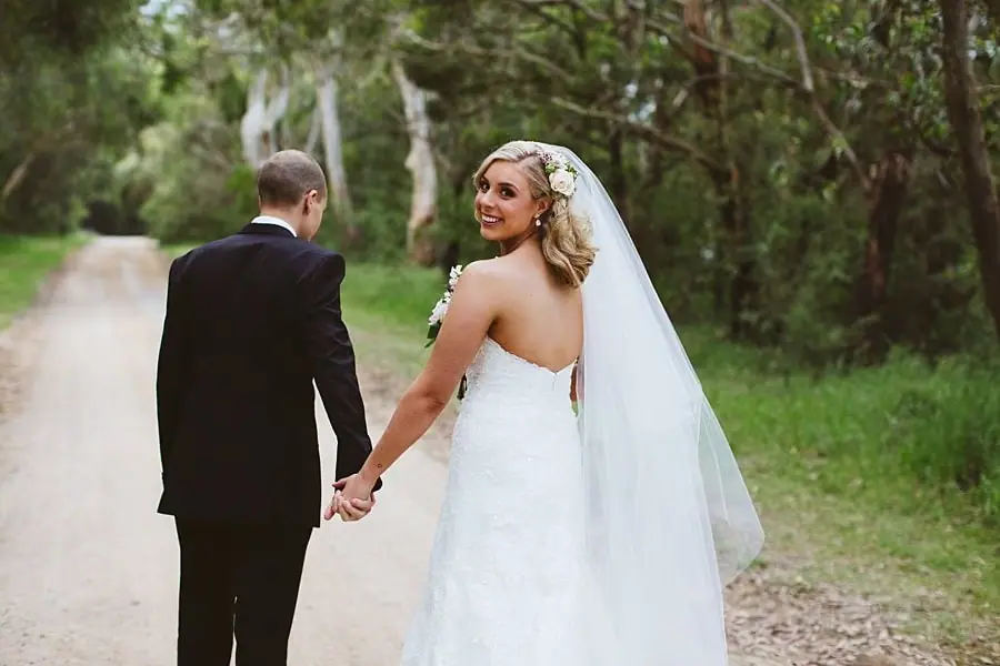 Bride looking back over her shoulder while walking hand in hand with the groom.