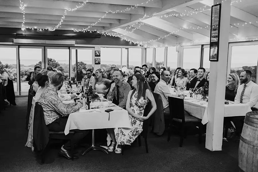 Black-and-white wide view of guests seated around a long reception table.