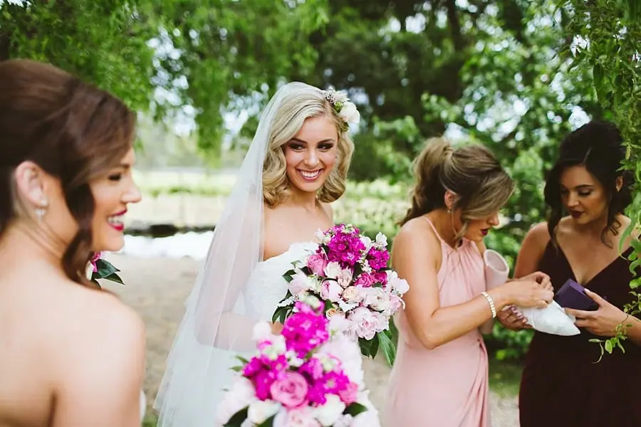 Bride smiling with bridesmaids nearby before the ceremony.