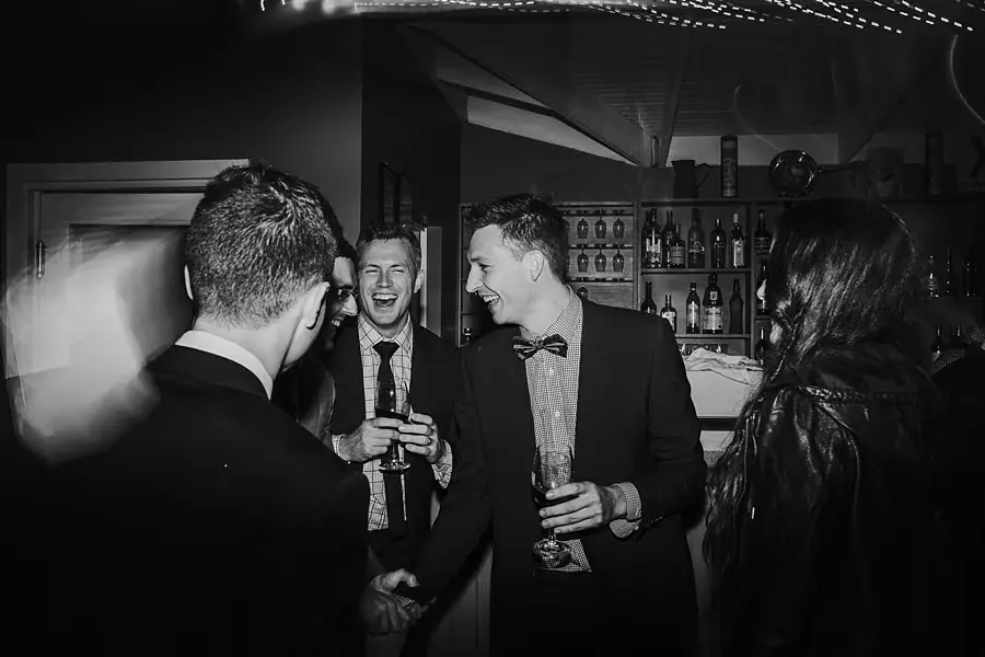 Black-and-white photograph of men talking together during the reception.