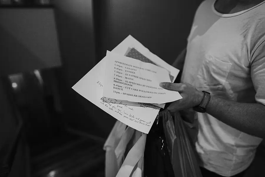Black-and-white close-up of a person holding handwritten and printed papers.