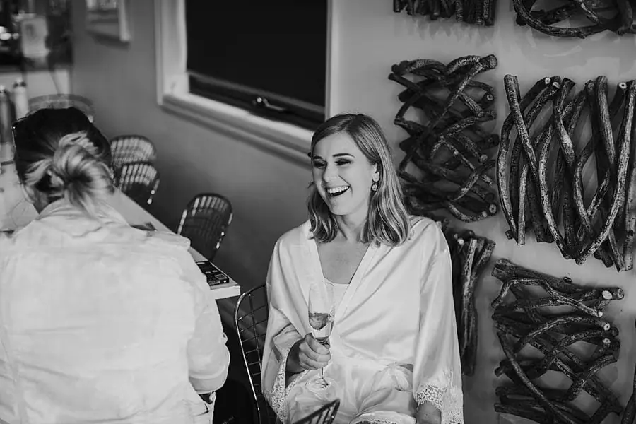 Black-and-white photograph of a woman laughing while seated in a robe.