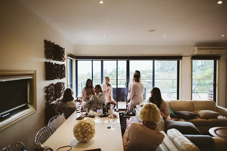 People gathered around a long table in a bright living room.