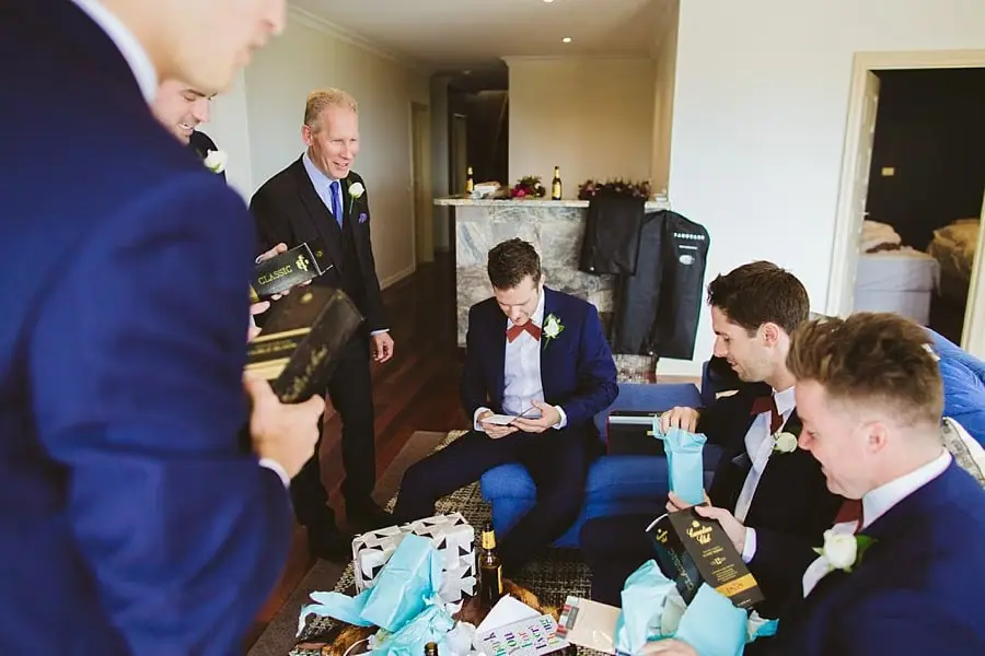 Suited men seated and standing around opened gifts.