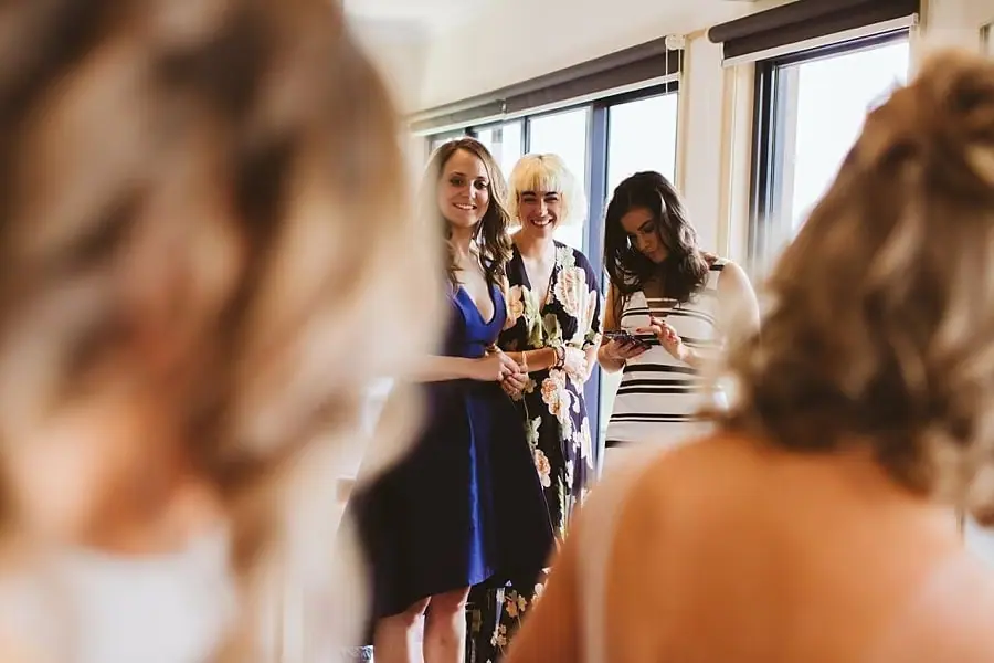 Guests smiling toward the bride in a bright living room.