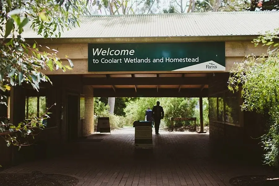 Covered building entrance with a welcome sign for wetlands and a homestead.