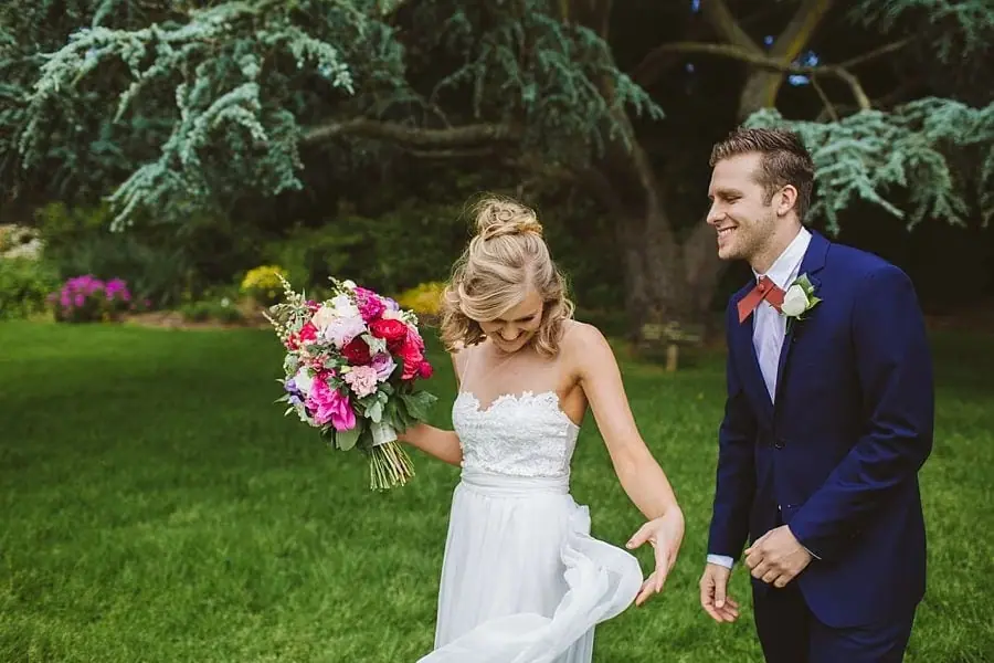 Bride laughing while lifting her skirt beside the groom.