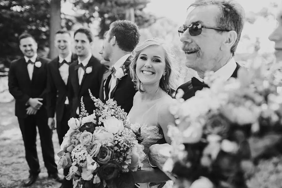 Black-and-white photograph of the bride with a man in sunglasses and suited companions.
