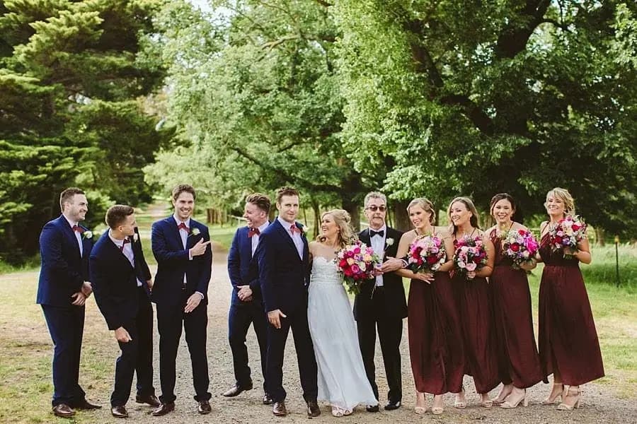 Wedding party chatting and laughing together on a garden path.
