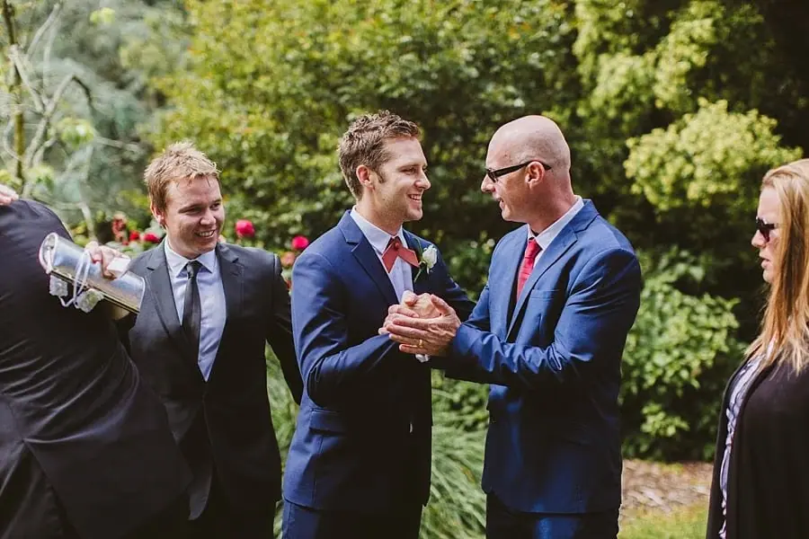Suited men greeting one another in a sunny garden.