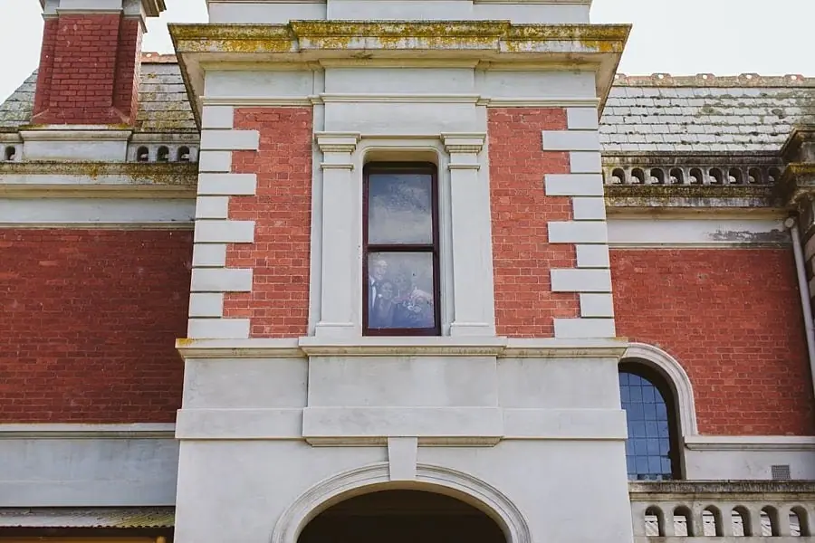 Architectural detail of a red brick house with pale trim and a projecting upper window.