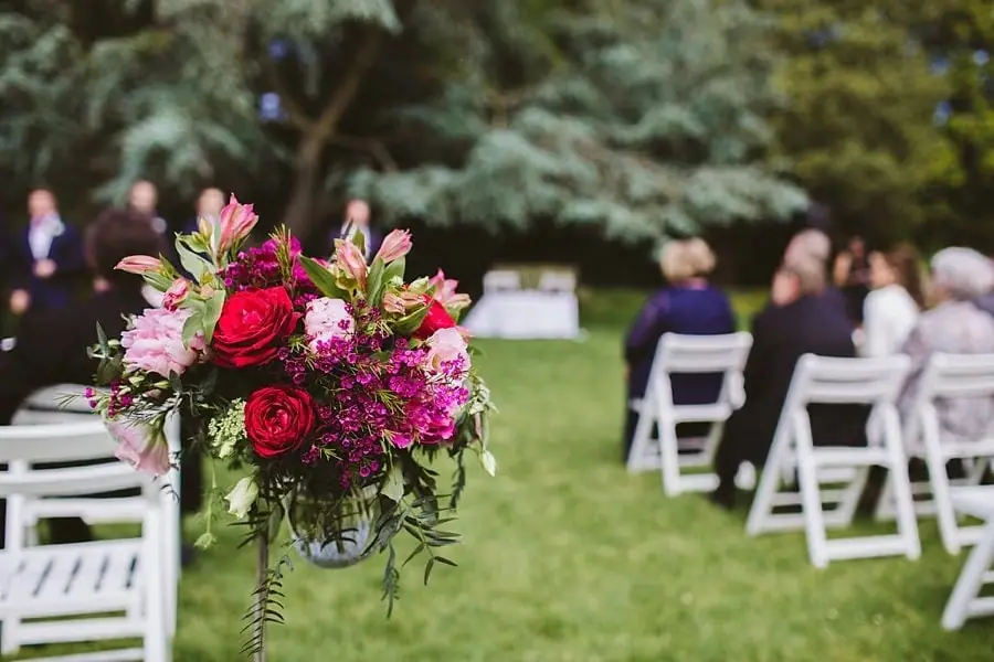 Bright pink and red flowers arranged beside outdoor ceremony seating.