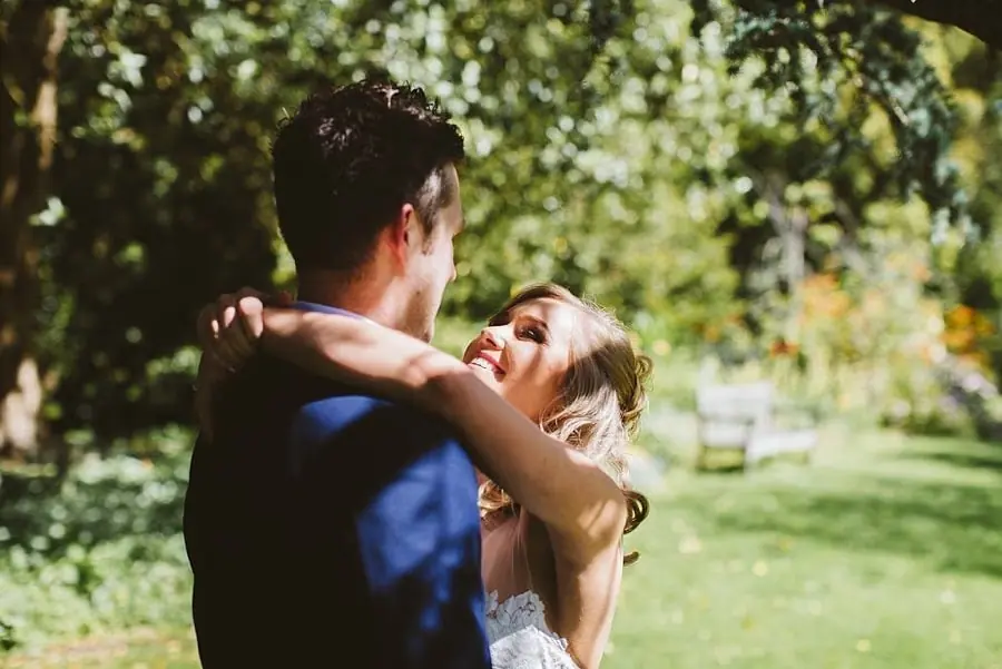 Bride reaching up to embrace a suited wedding guest.