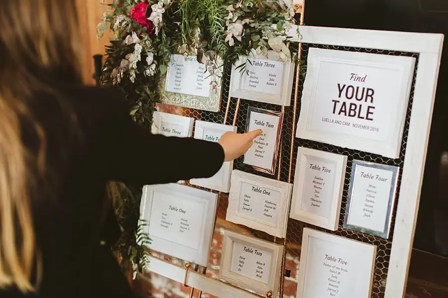 Guest pointing toward a flower-decorated reception seating chart.