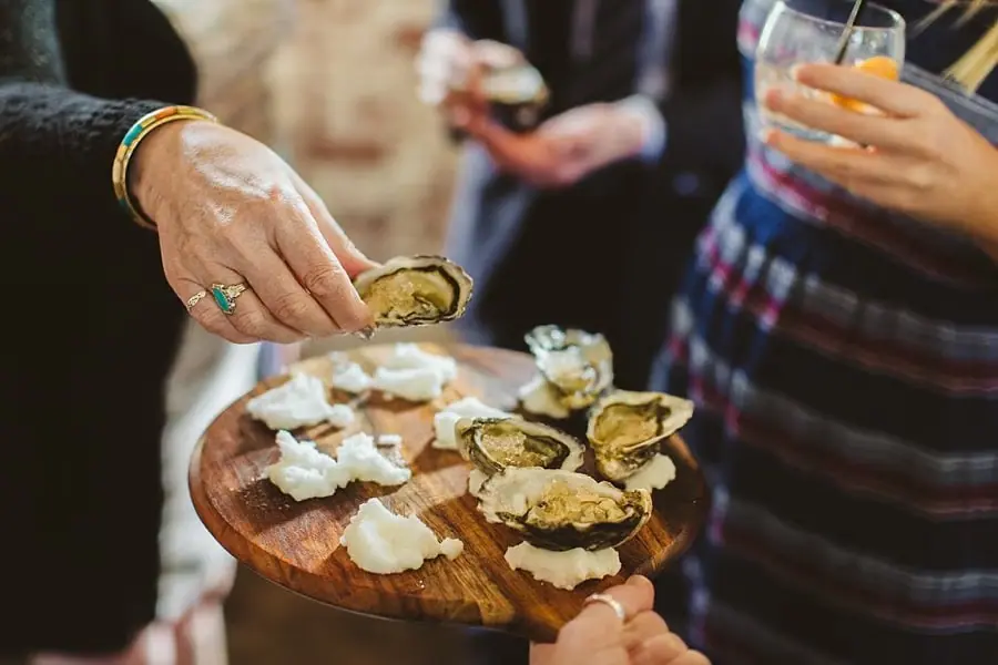 Close-up of a hand reaching toward a platter of small appetizers.