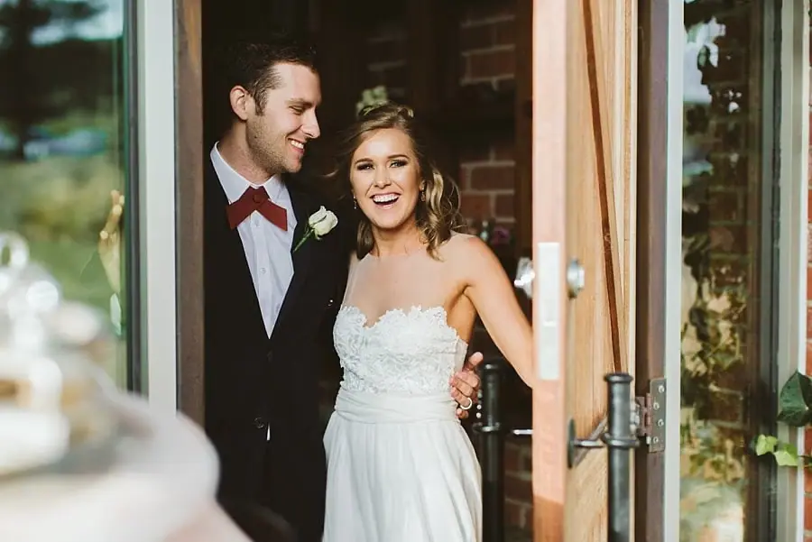Bride and groom smiling in an open doorway.