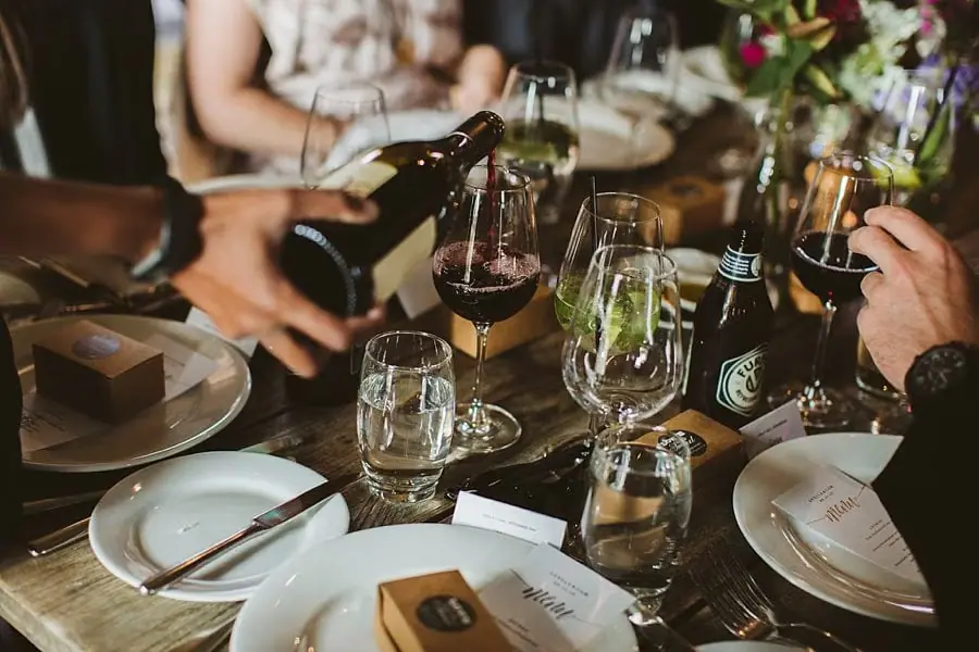 Close-up of wine being poured over a wooden reception table.