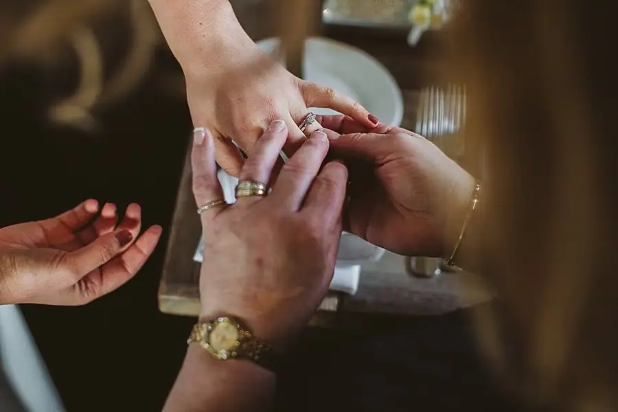 Close-up of hands showing a ring above a reception table.