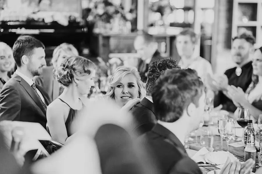 Black-and-white photograph of women smiling among seated reception guests.