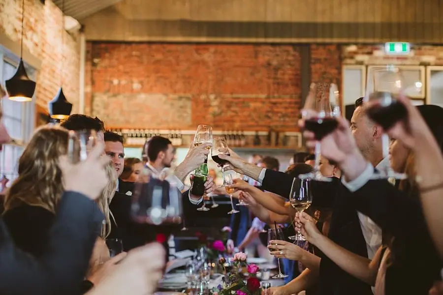 Guests raising wine glasses over a long reception table.