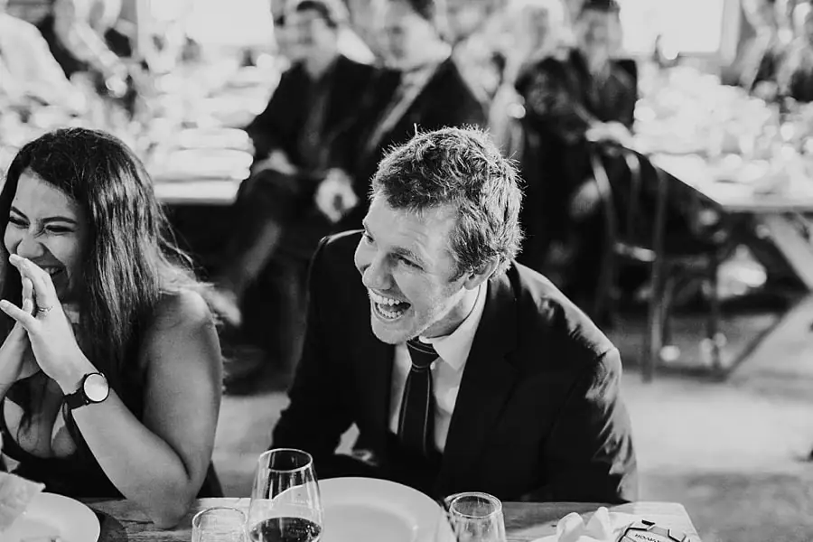 Black-and-white photograph of two guests laughing at their table.