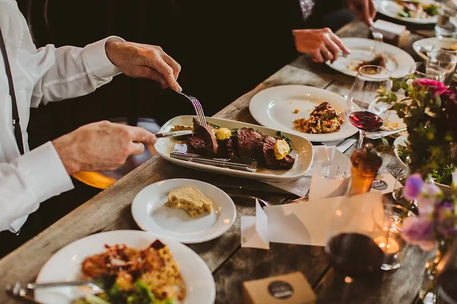 Guests serving food from a shared platter at a reception table.
