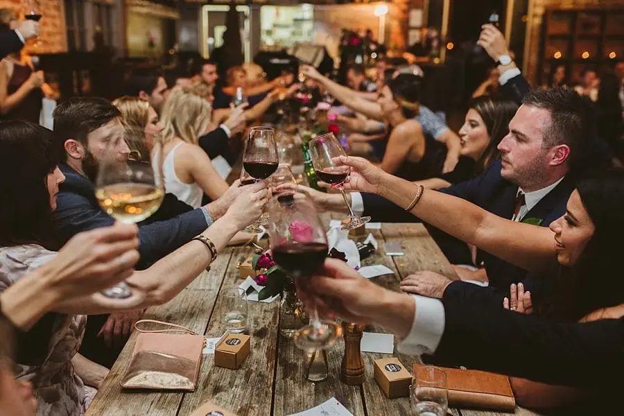 Wedding guests raising glasses across a decorated reception table.