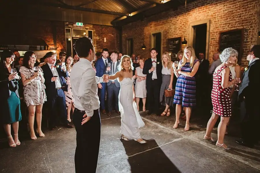 Bride approaching the groom on a dance floor surrounded by guests.