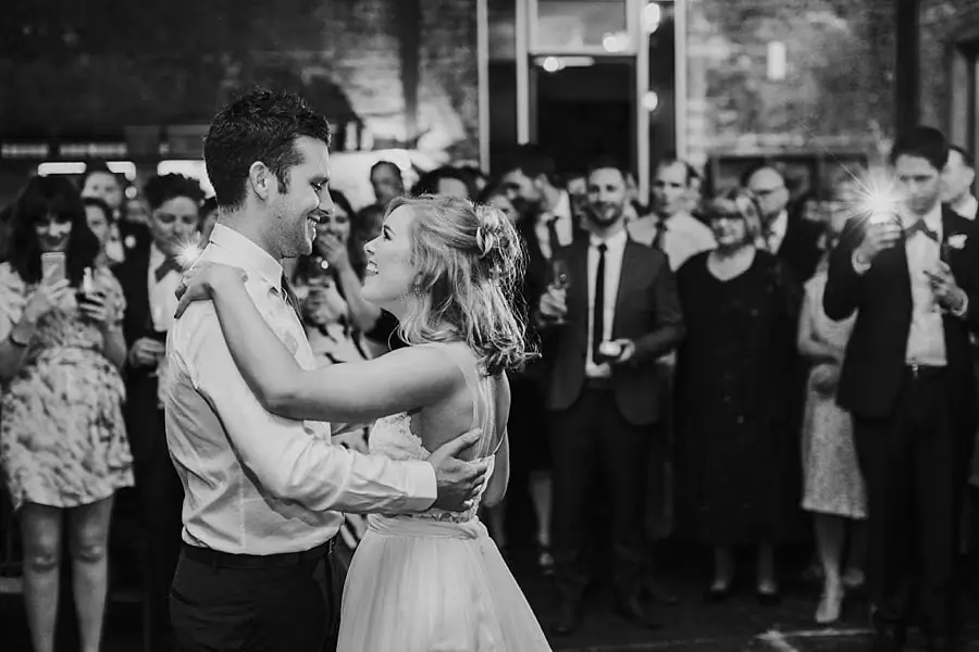 Black-and-white photograph of the couple dancing while guests watch.