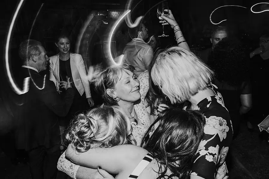 Black-and-white photograph of women dancing together beneath streaks of light.