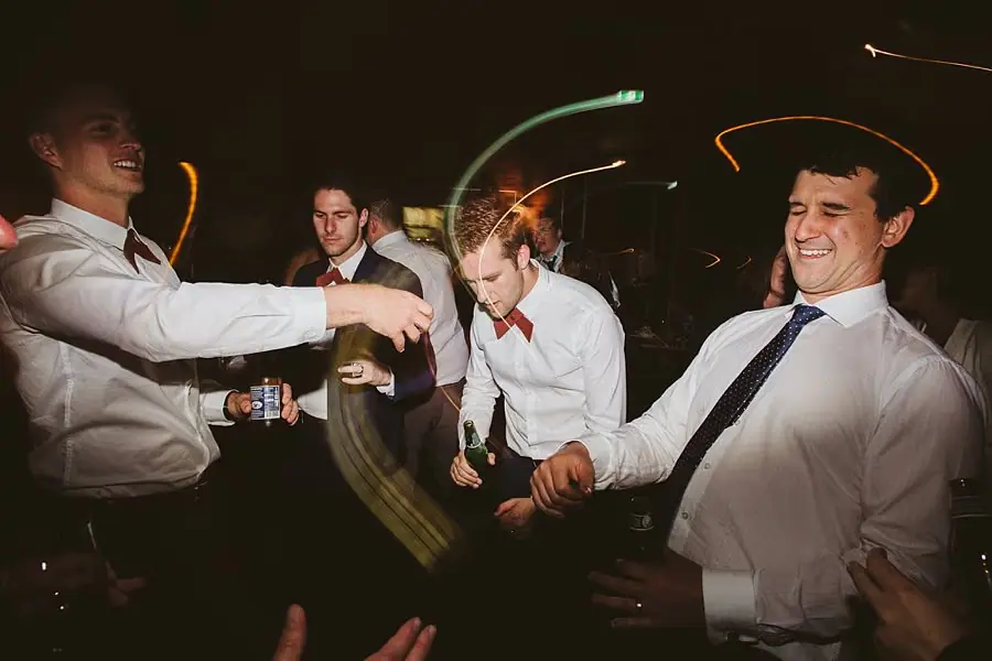 Men in shirts and ties dancing beneath motion-blurred lights.