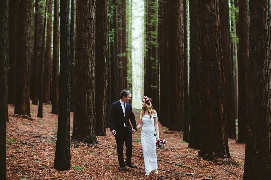Bride and groom walking side by side along the redwood forest floor.
