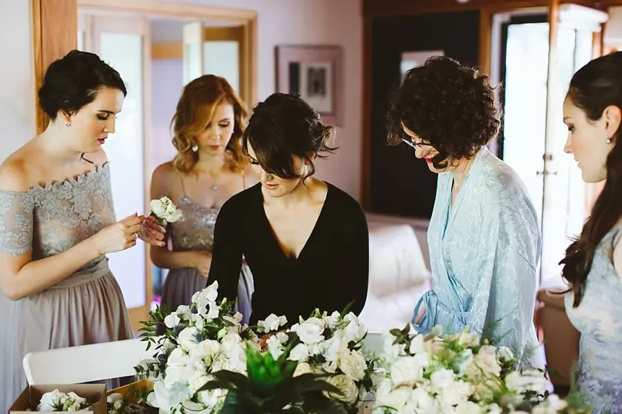 Women gathered around white wedding bouquets indoors.