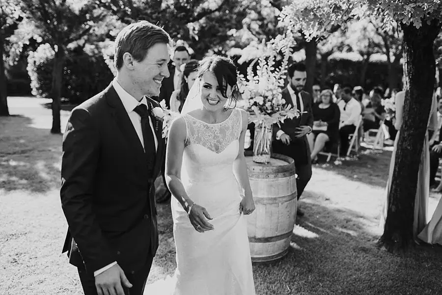Black-and-white photograph of the bride and groom smiling during the ceremony.