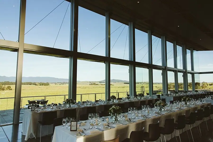 Reception tables beside tall windows overlooking fields and hills.