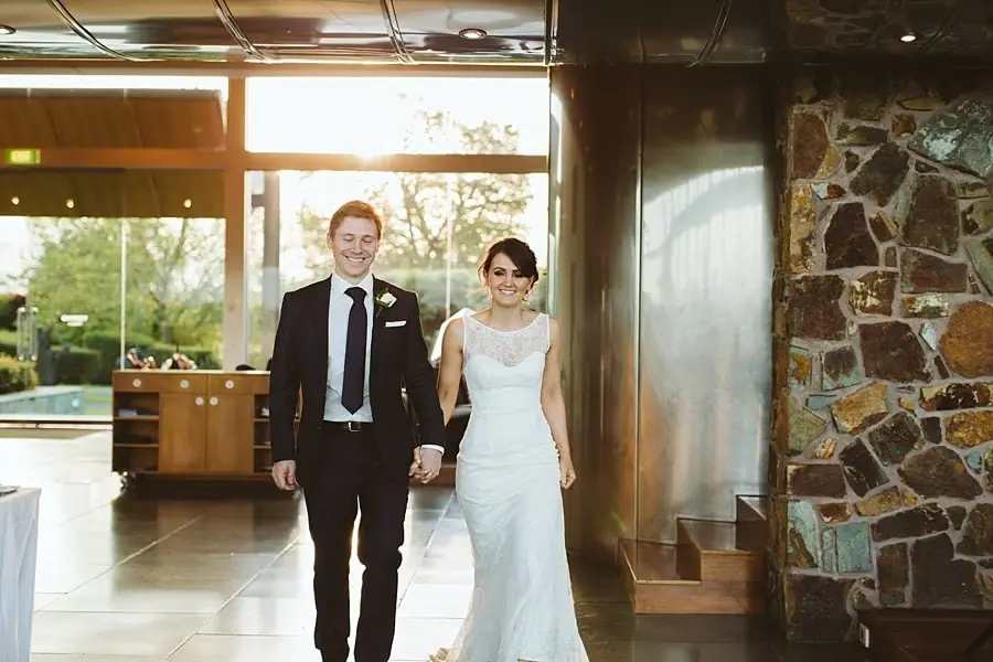 Bride and groom walking hand in hand into the reception room.