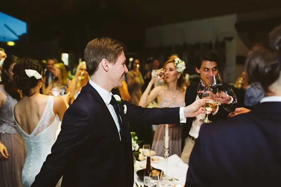Groom raising a glass toward guests during the reception.