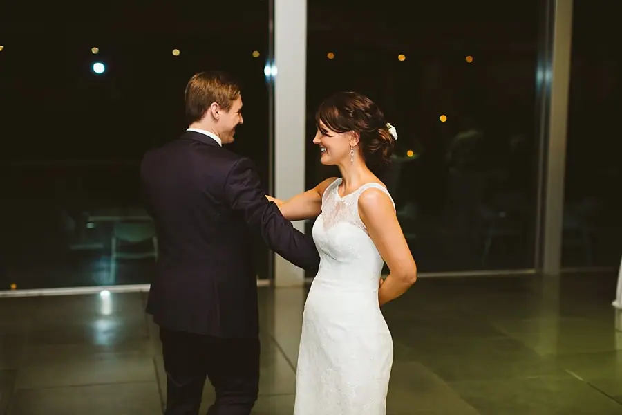 Bride and groom smiling at each other as they dance in the reception room.