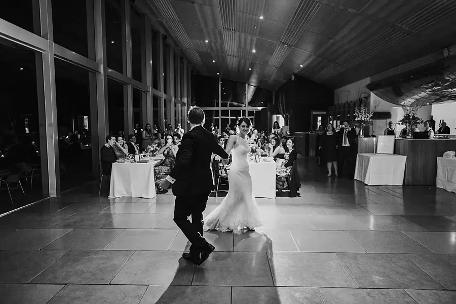 Black-and-white photograph of the couple dancing while seated guests watch.
