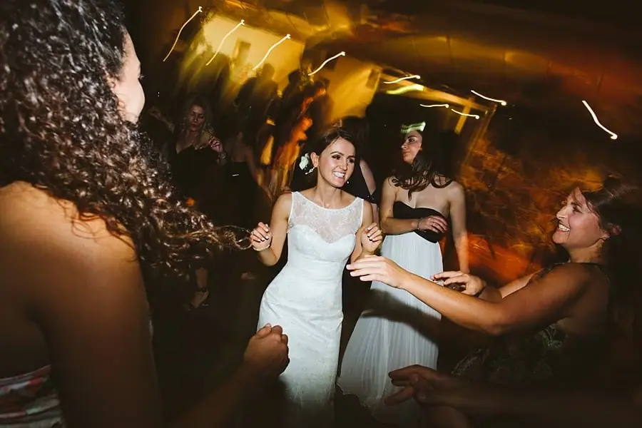 Bride smiling as she dances with women at the reception.
