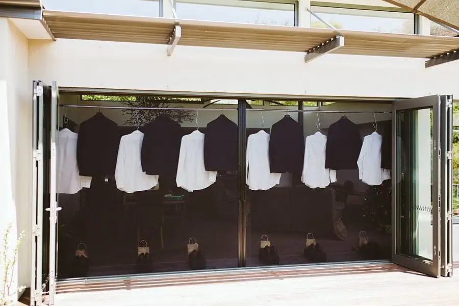 Dark suit jackets and white shirts hanging across an open folding doorway.