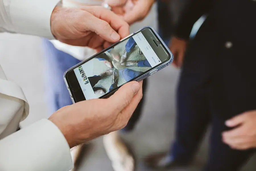 Hands holding a phone displaying a close-up photograph of footwear.