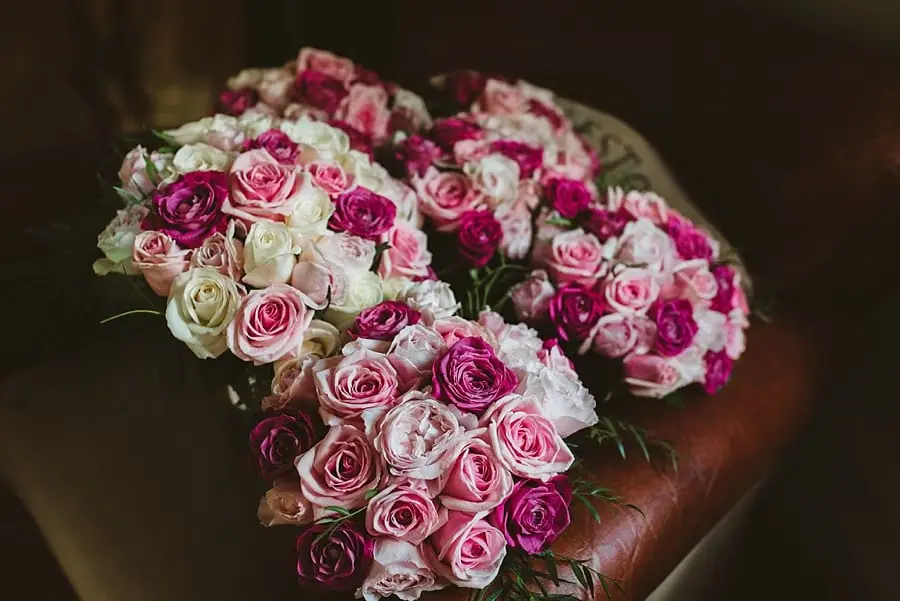 Pink and white rose bouquets arranged on a dark leather chair.