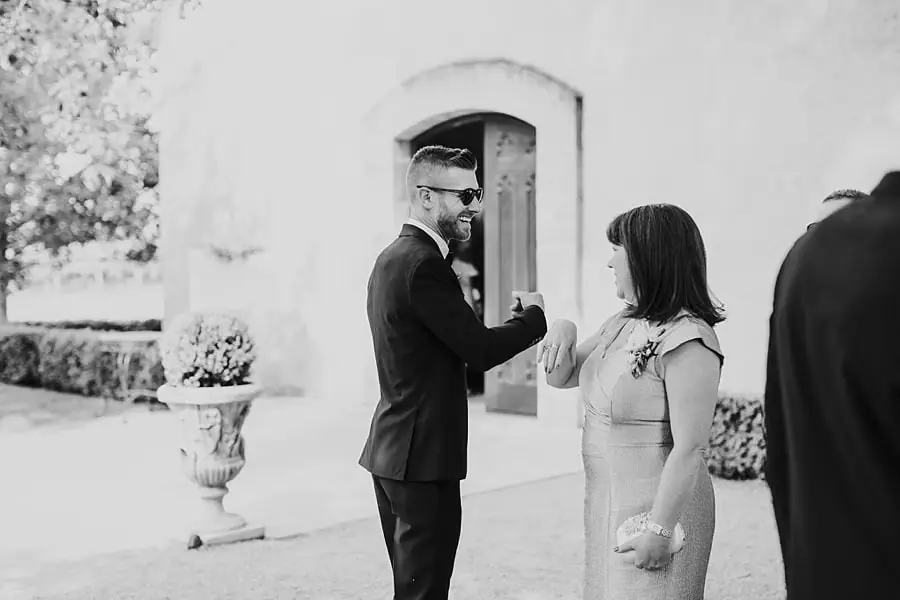 Black-and-white photograph of a suited man and a woman greeting each other outside the chapel.