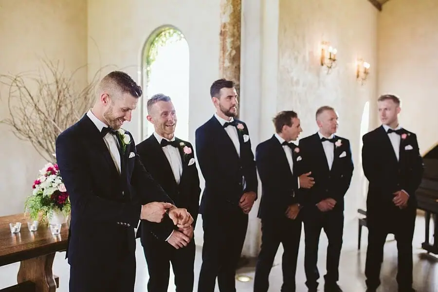 Groom and five suited men waiting at the front of the chapel.