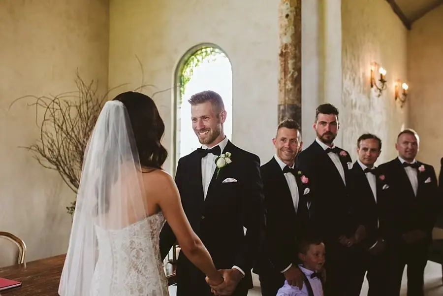 Bride and groom facing each other and holding hands at the front of the chapel.