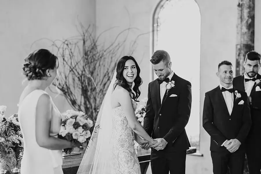 Black-and-white photograph of the bride smiling beside the groom during the ceremony.